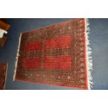 A 20TH CENTURY WOOLLEN KAZAK RED GROUND RUG, 171cm x 125cm