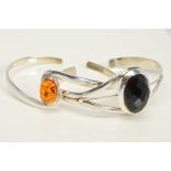 TWO TORQUE BANGLES, the first of crossover design set with a central oval modified amber cabochon,