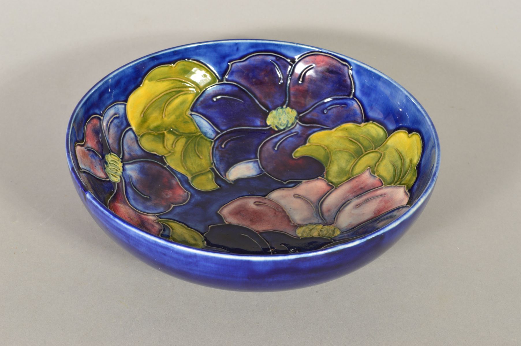 A MOORCROFT POTTERY FOOTED BOWL, 'Clematis' pattern on blue ground, impressed marks, Queen Mary