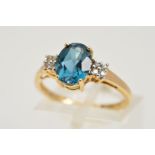 A 9CT GOLD GEM RING, designed as a central oval topaz in a four claw setting flanked by a cluster of