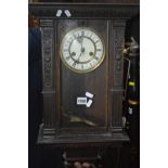 AN EARLY 20TH CENTURY OAK WALL CLOCK with an enamel dial and Roman numerals (winding key)
