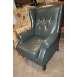 A GREEN LEATHER BUTTONED WING BACK ARMCHAIR