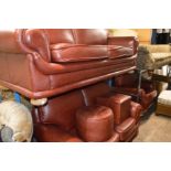 A RED LEATHER THREE PIECE LOUNGE SUITE comprising of a two seater settee and smaller two seater
