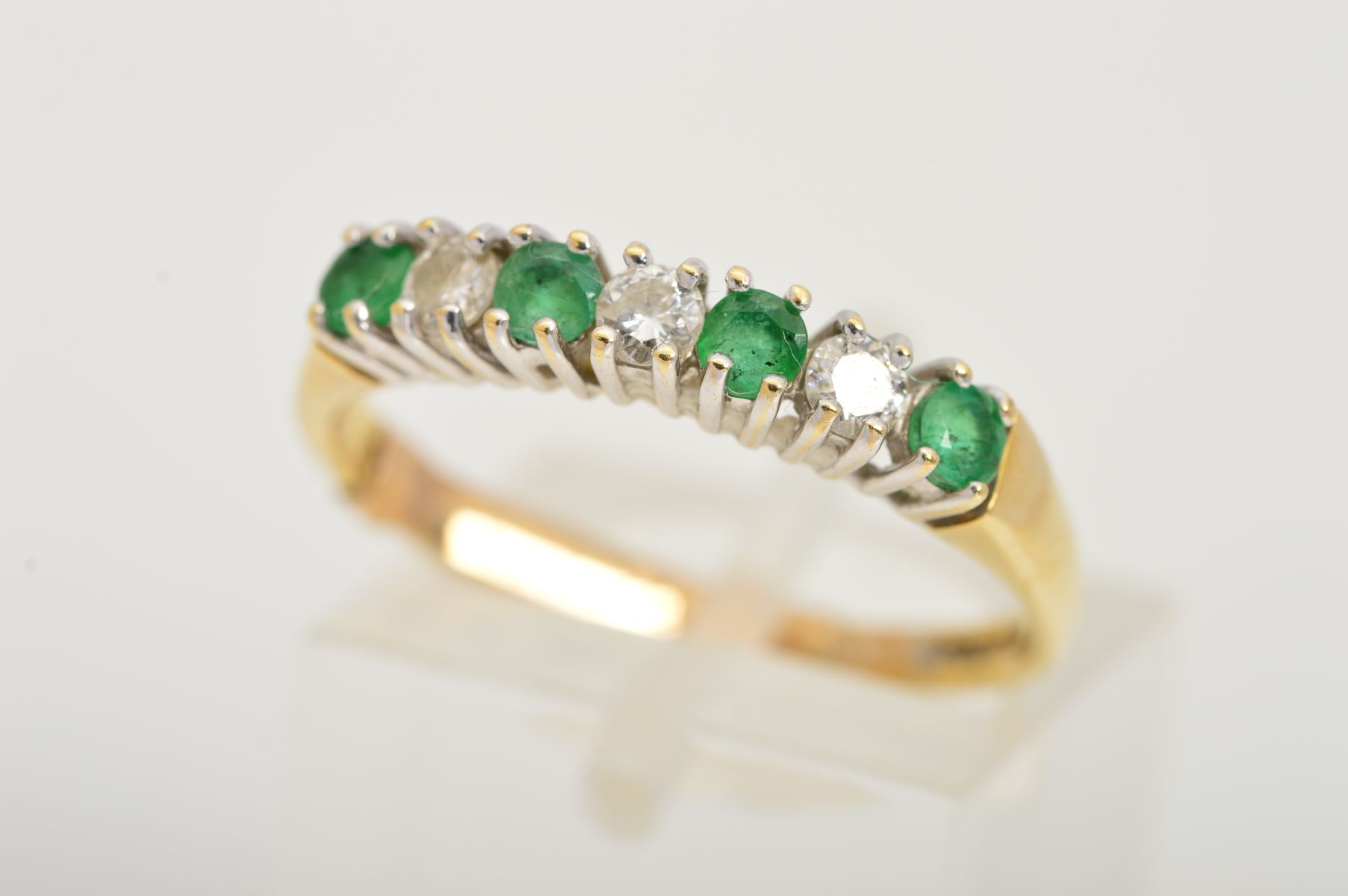 AN 18CT GOLD EMERALD AND DIAMOND RING, designed as a row of four circular emeralds interspaced by