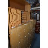 A LARGE TEAK SCHOOL LOCKER made up of twenty one cupboards, width 224cm x depth 39cm x height