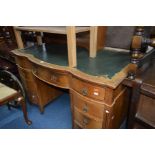 AN EARLY 20TH CENTURY OAK SERPENTINE DESK with a green tooled leather top and nine drawers, on brass