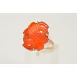 A CARVED CARNELIAN RING, the carved and pierced carnelian panel within a four claw setting to the