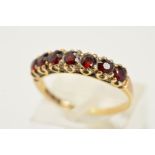 A 9CT GOLD GARNET RING, set with a row of seven circular cut to the plain polished band, with 9ct