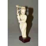 A LATE 19TH CENTURY JAPANESE IVORY OKIMONO, carved as a lady standing holding a vase of flowers,