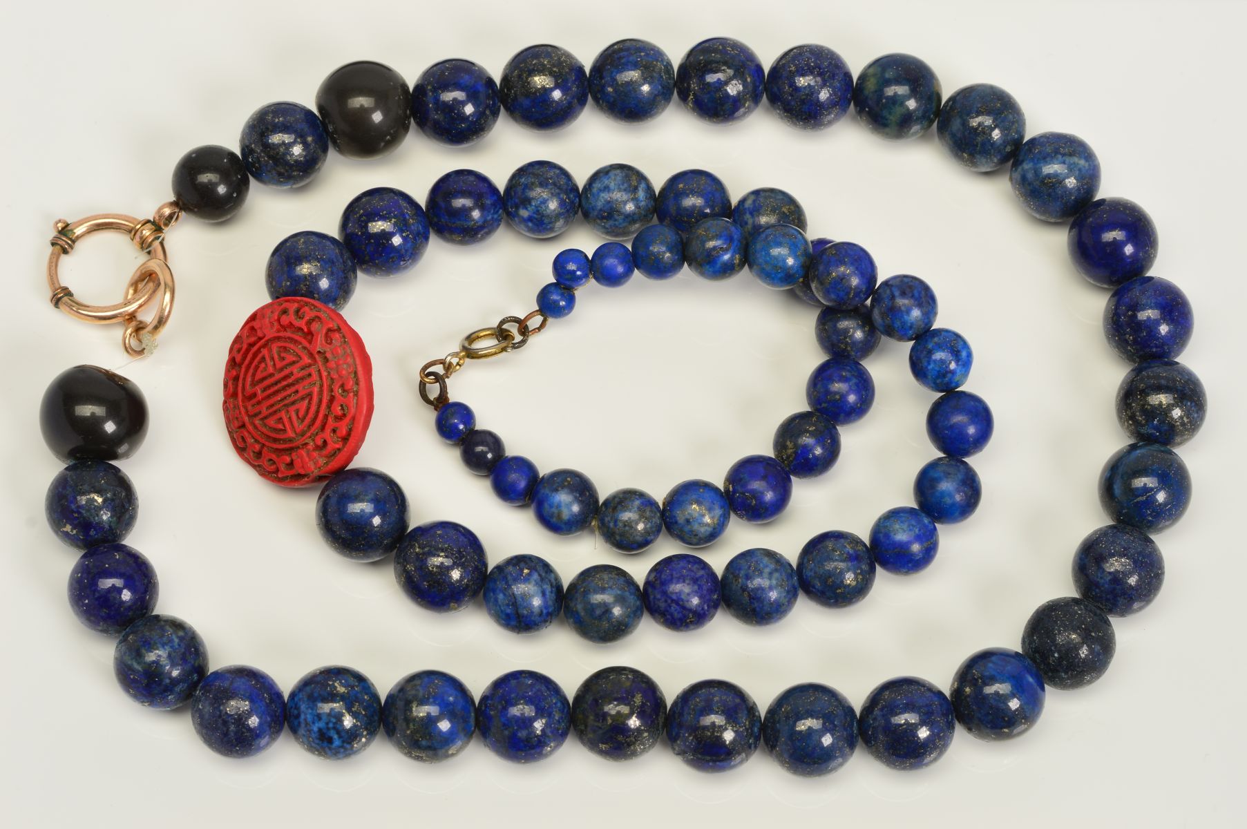 TWO SINGLE ROW LAPIS LAZULI BEAD NECKLACES, the first designed as a near uniform row of spherical