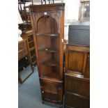 A SLIM JAYCEE OPEN CORNER CUPBOARD with carved detailing to the top arched frieze and the single