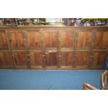 A LATE 19TH/EARLY 20TH CENTURY PINE AND MAHOGANY LOCKER, with seventeen panelled cupboard doors,