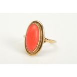 A 9CT GOLD CORAL RING, designed as an elongated oval coral cabochon within a collet setting and rope