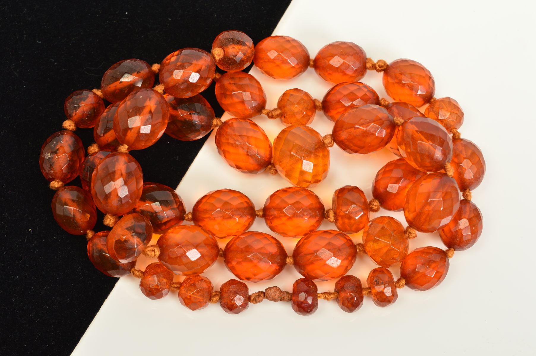 A FACETED AMBER BEAD NECKLACE, designed as oval and spherical faceted amber beads measuring