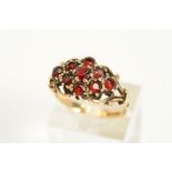 A 9CT GOLD GARNET RING, set with nine circular cut garnets with scroll design bifurcated