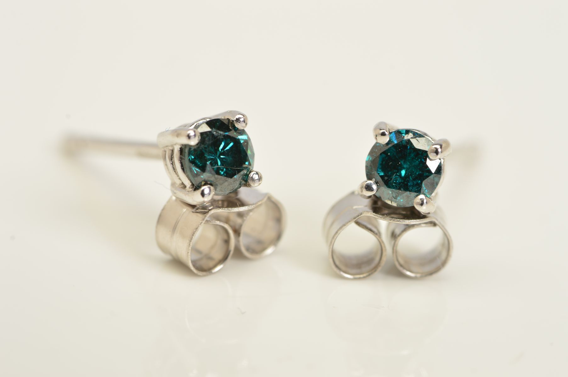 A PAIR OF 18CT GOLD TREATED BLUE DIAMOND STUD EARRINGS, each designed as a single brilliant cut