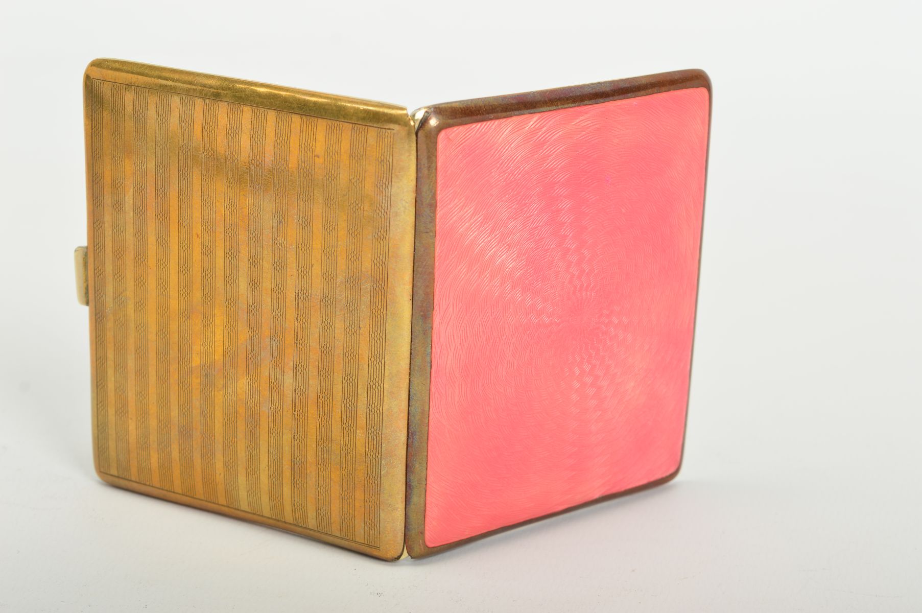 A GOLD PLATED AND PINK ENAMEL CIGARETTE CASE, engine turned decoration back and front, gilt