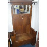 AN ARTS AND CRAFTS STYLE OAK HALL STAND/SEAT, with a rectangular bevelled mirror, various coat
