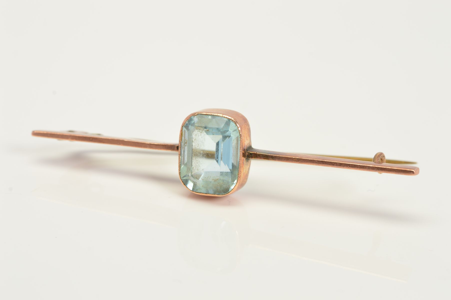 AN EARLY 20TH CENTURY GOLD BAR BROOCH, centrally set with a rectangular blue paste in a collet