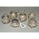 AN INDIAN WHITE METAL SIX PIECE CRUET SET, foliate repousse decoration to the globular bodies (6)