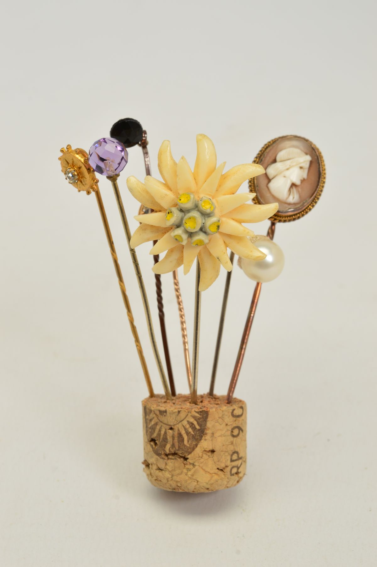 SEVEN STICKPINS, to include a faceted amethyst stickpin, an oval cameo stickpin, a bone flower