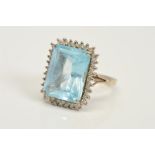 AN 18CT WHITE GOLD TOPAZ AND DIAMOND CLUSTER RING, designed as a rectangular blue topaz within a