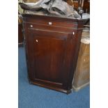 A GEORGIAN OAK HANGING CORNER CUPBOARD, with a raised panel single door and a reeded detail to