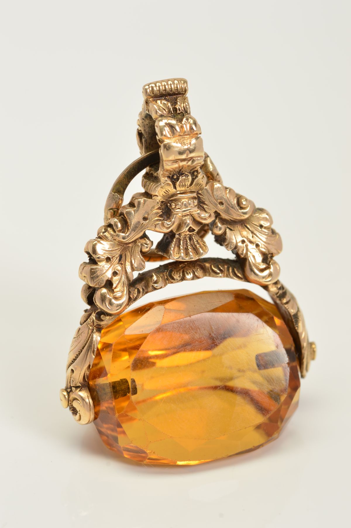 A CITRINE SWIVEL FOB, the faceted triangular citrine with a decorative acanthus leaf grip, height