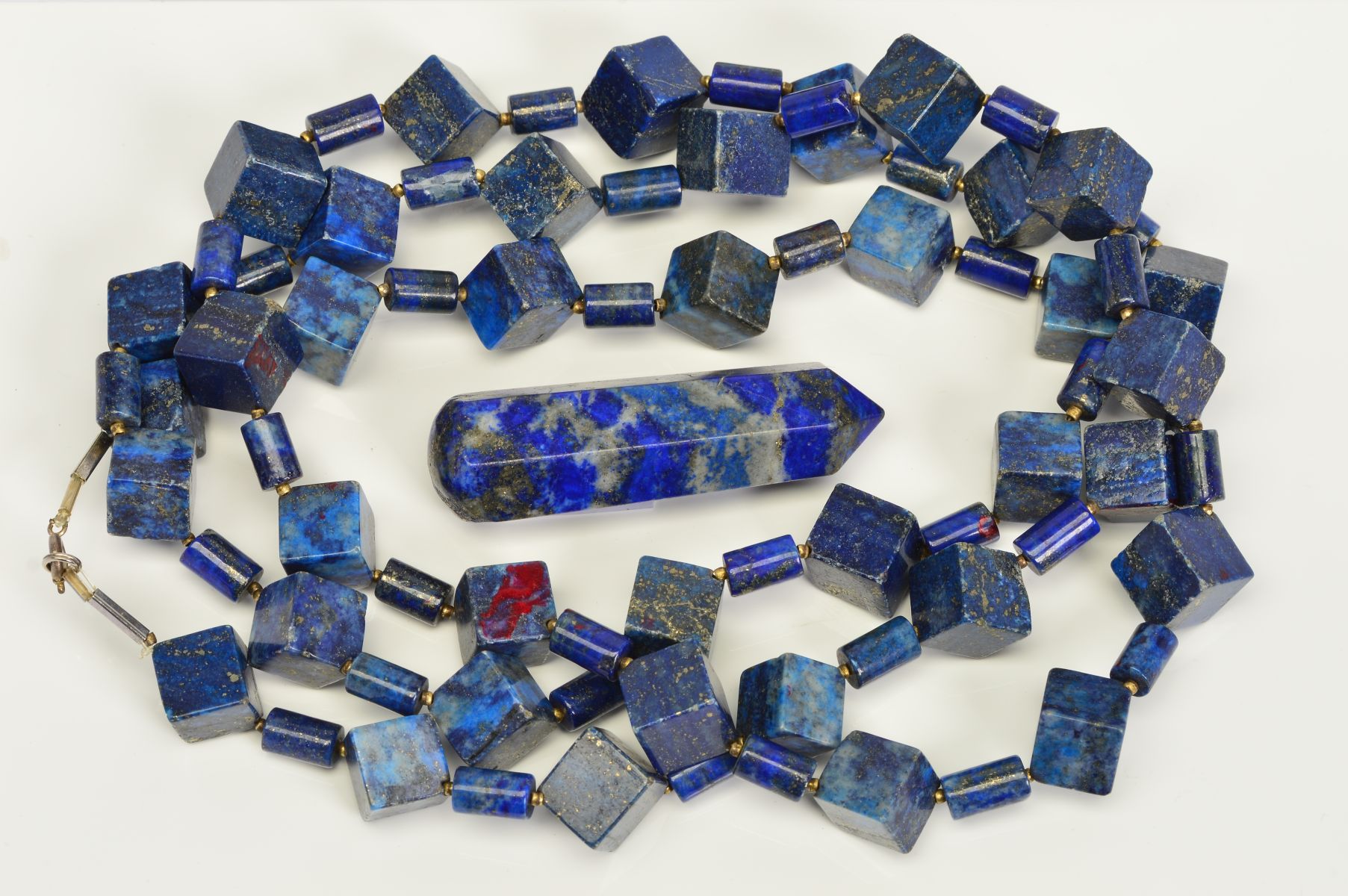 A LONG LAPIS LAZULI BEAD NECKLACE AND A LAPIS LAZULI PAPERWEIGHT, the necklace designed as cube