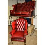 AN OX BLOOD LEATHER BUTTONED WING BACK THREE SEATER SETTEE on cabriole legs together with a matching