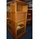 A LIGHT OAK FOUR SECTION BOOKCASE, three sections with glazed doors and one section with a