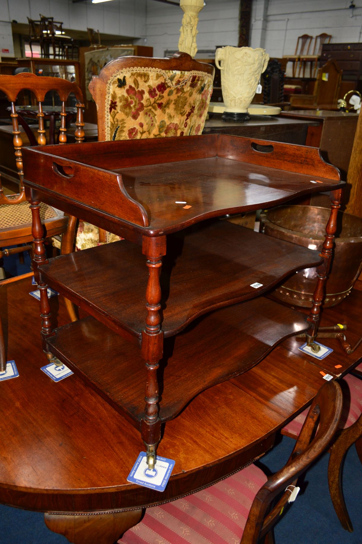 A LOW EARLY 19TH CENTURY MAHOGANY THREE TIER STAND, gallery top with twin carrying handles, turned