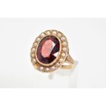 A MODERN GARNET AND SEED PEARL OVAL CLUSTER RING, garnet measuring approximately 15.5mm x 10.5mm,
