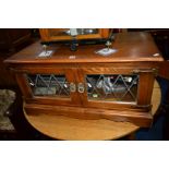 AN OLD CHARM OAK TWO DOOR TV CABINET with contents (sd to glass)