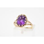 A 9CT GOLD AMETHYST RING, designed with a central oval cut amethyst within a scallop surround to the
