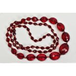 A FACETED RED PLASTIC BEAD NECKLACE, designed as a single row of graduated oval faceted red