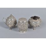 AN INDIAN WHITE METAL THREE PIECE CRUET SET, embossed with foliate scrolls (3)