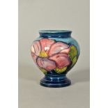 A SMALL MOORCROFT POTTERY FOOTED VASE/URN, 'Clematis' pattern on blue ground, Queen Mary paper label