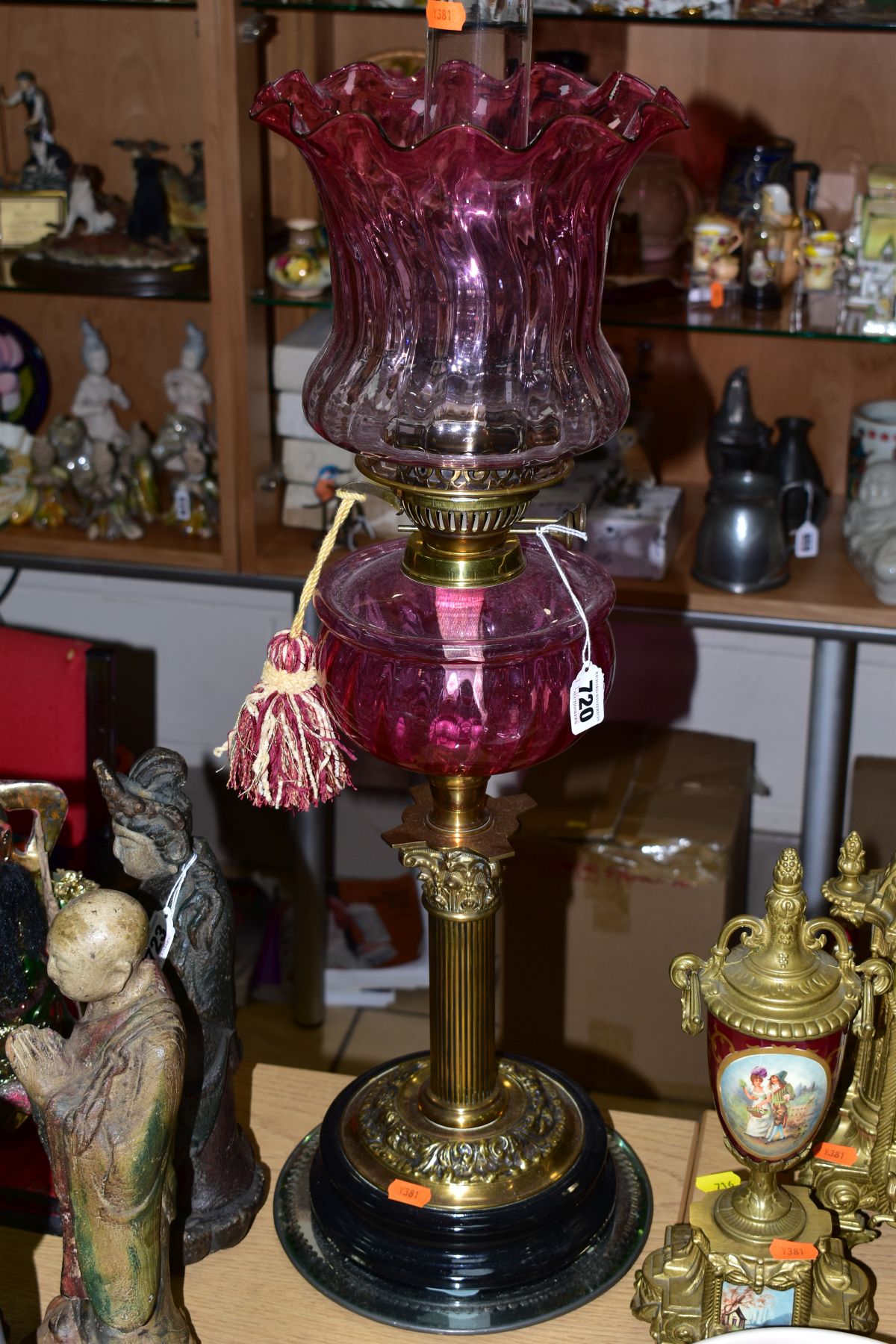 AN EARLY 20TH CENTURY BRASS AND CRANBERRY GLASS OIL LAMP, having Corinthian brass column,