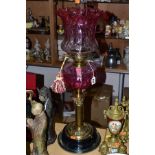 AN EARLY 20TH CENTURY BRASS AND CRANBERRY GLASS OIL LAMP, having Corinthian brass column,