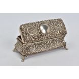 AN EDWARDIAN SILVER TRINKET BOX OF RECTANGULAR BOMBE FORM, foliate repousse decoration, on four