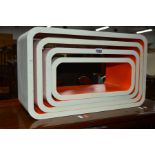 A SET OF FOUR GRADUATING WHITE AND ORANGE GROUND RECTANGULAR WALL SHELVES with rounded corners,