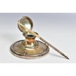 AN EDWARDIAN SILVER CAPSTAN INKWELL FITTED WITH A PEN REST, the hinged cover over a clear glass