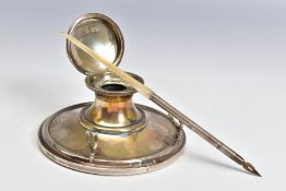 AN EDWARDIAN SILVER CAPSTAN INKWELL FITTED WITH A PEN REST, the hinged cover over a clear glass