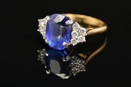 A MODERN 18CT GOLD TANZANITE AND DIAMOND DRESS RING, centring on a principal cushion cut tanzanite