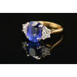 A MODERN 18CT GOLD TANZANITE AND DIAMOND DRESS RING, centring on a principal cushion cut tanzanite