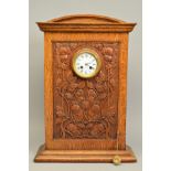 AN ARTS & CRAFTS OAK CASED MANTEL CLOCK, the domed top above a rectangular case carved with entwined