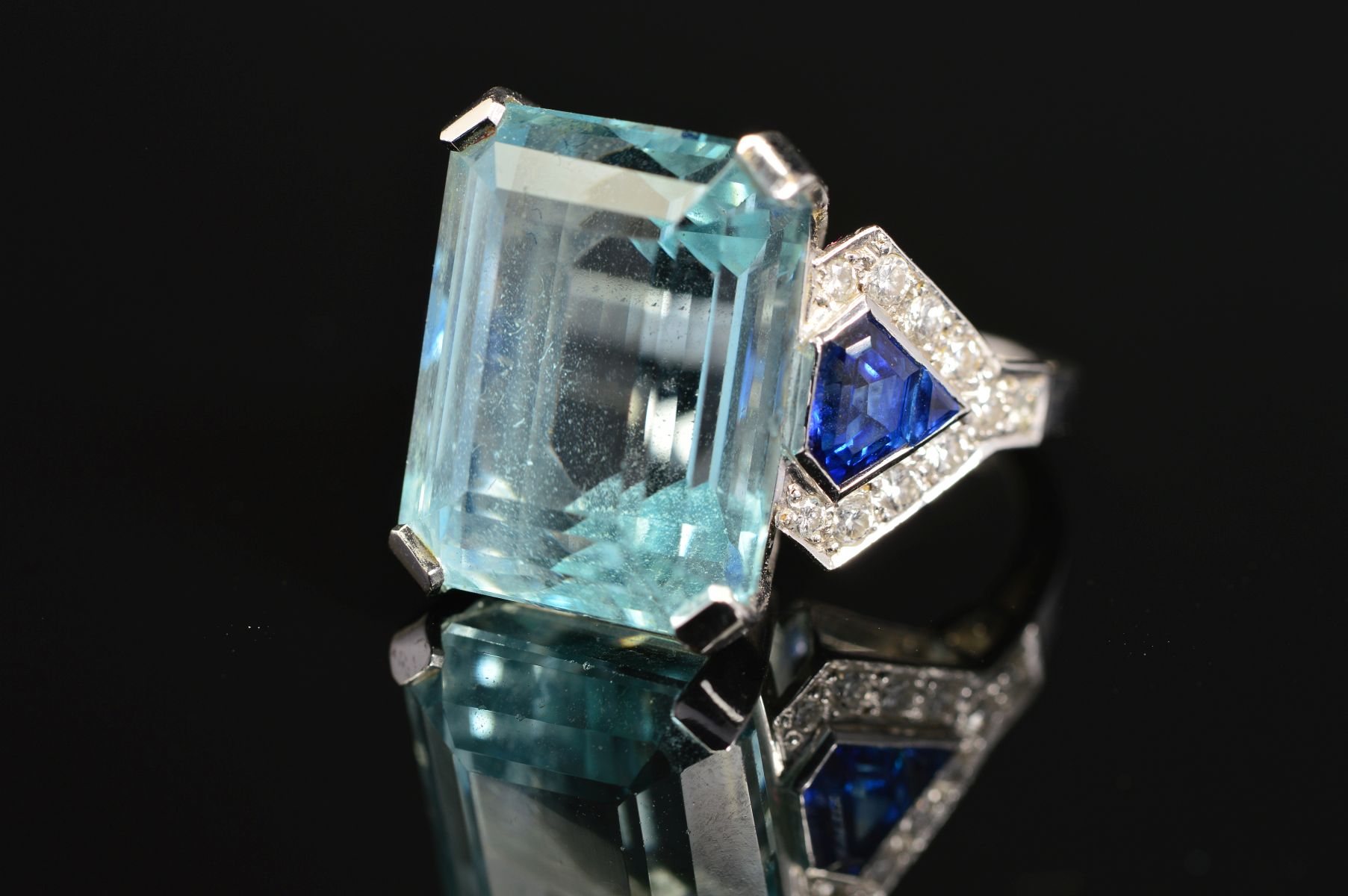 A MODERN AQUAMARINE, SAPPHIRE AND DIAMOND DRESS RING, centring on a principal trap cut aquamarine