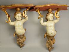 A PAIR OF LATE 19TH/EARLY 20TH CENTURY GILDED AND PAINTED WOODEN PUTTI SUPPORT WALL SHELVES, the