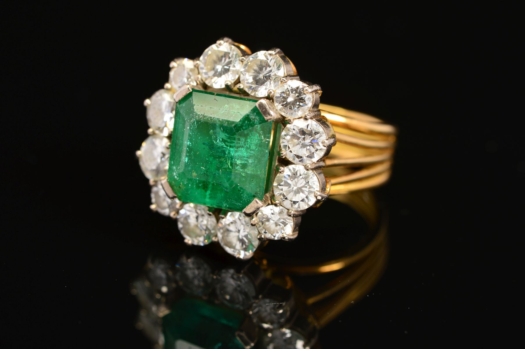 A LATE 20TH CENTURY LARGE EMERALD AND DIAMOND CLUSTER RING, emerald cut emerald measuring